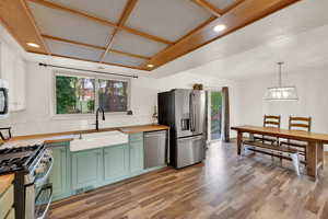 Kitchen featuring wooden counters, backsplash, light wood-style floors, stainless steel appliances, and green cabinets
