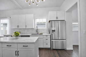 Updated main kitchen featuring stainless steel refrigerator with ice dispenser, white cabinets, tasteful backsplash, and dark wood finished floors
