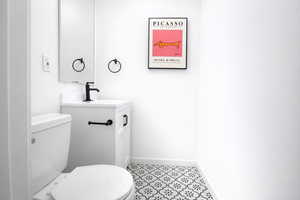 Main floor powder room featuring vanity and light tile patterned flooring. One of four total bathrooms.