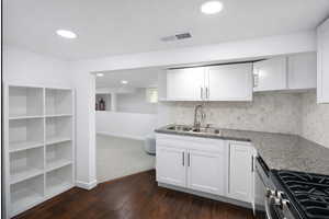 ADU kitchen with white cabinets, dark wood-style floors, recessed lighting, and backsplash