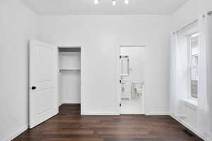 Main floor bedroom with dark wood-style floors and a spacious closet