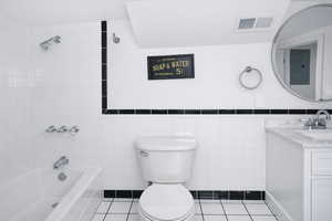 ADU bathroom with vanity, tile walls, light tile patterned floors, electric panel, and bathing tub / shower combination