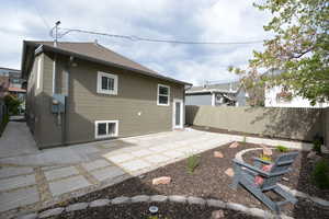 Rear view of house with a patio, a fenced backyard, and a shingled roof