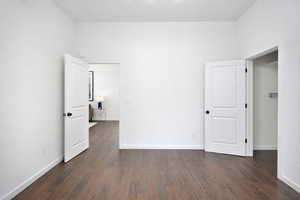 Main floor bedroom featuring dark wood finished floors and baseboards
