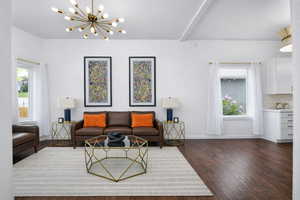 Living area with a chandelier and dark wood-type flooring