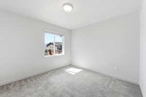Spare room with light carpet and baseboards