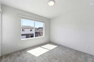 Empty room featuring light carpet and a smoke detector