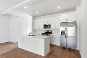 Kitchen with stainless steel appliances, dark wood-style flooring, a center island with sink, white cabinets, and recessed lighting