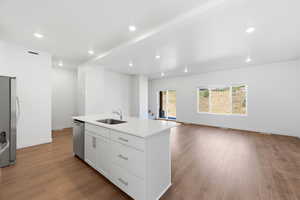 Kitchen featuring open floor plan, a kitchen island with sink, dark wood-style flooring, white cabinets, and recessed lighting