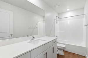 Full bath with vanity, dark wood-style flooring, and  shower combination