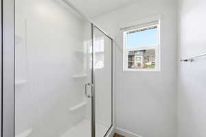 Bathroom with a shower stall and baseboards