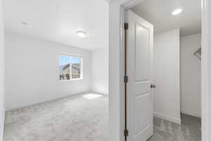 Unfurnished bedroom featuring light carpet and baseboards