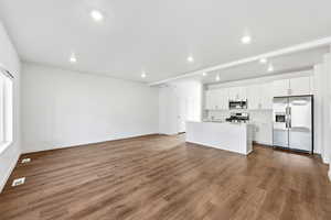 Unfurnished living room with dark wood-type flooring and recessed lighting