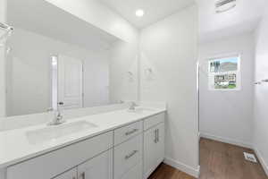 Full bath with double vanity, dark wood finished floors, and recessed lighting
