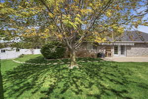 Rear view of property with brick siding, a fenced backyard, french doors, a patio area, and roof with shingles