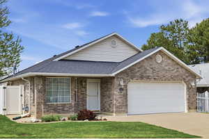 Ranch-style house featuring a garage, driveway, a gate, brick siding, and roof with shingles