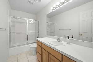 Full bathroom with vanity, light tile patterned flooring, and bath / shower combo with glass door
