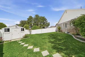 Fenced backyard featuring a storage shed