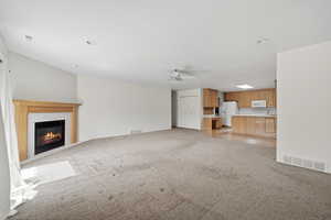 Unfurnished living room with a fireplace, ceiling fan, and light colored carpet