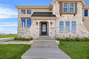 View of front of home featuring stone siding, a standing seam roof, and a front yard