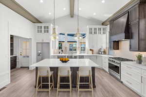 Dual tone kitchen featuring decorative backsplash, stainless steel appliances, a breakfast bar, light wood finished floors, and light stone counters