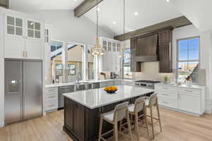 Dual tone kitchen with stainless steel appliances, tasteful backsplash, a kitchen bar, light wood-style flooring, and dual tone cabinetry