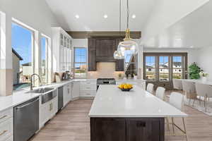Dual tone kitchen with light stone countertops, two tone cabinetry, decorative backsplash, a kitchen breakfast bar, and stainless steel appliances