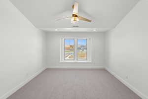 Carpeted spare room with a ceiling fan and baseboards