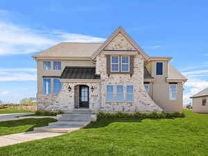 View of front of house with stone siding, a front lawn, and a standing seam roof