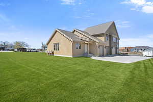 Back of property with stucco siding, a lawn, concrete driveway, a shingled roof, and a residential view