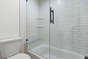 Bathroom featuring toilet and enclosed tub / shower combo