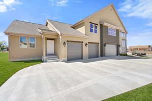 View of front of property with driveway, roof with shingles, stucco siding, a front lawn, and an attached garage