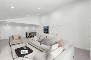 Living area featuring carpet flooring, recessed lighting, and vaulted ceiling