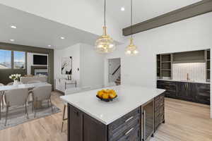 Kitchen with dark wood finish cabinets, open floor plan, light stone countertops, a kitchen island, and a kitchen breakfast bar