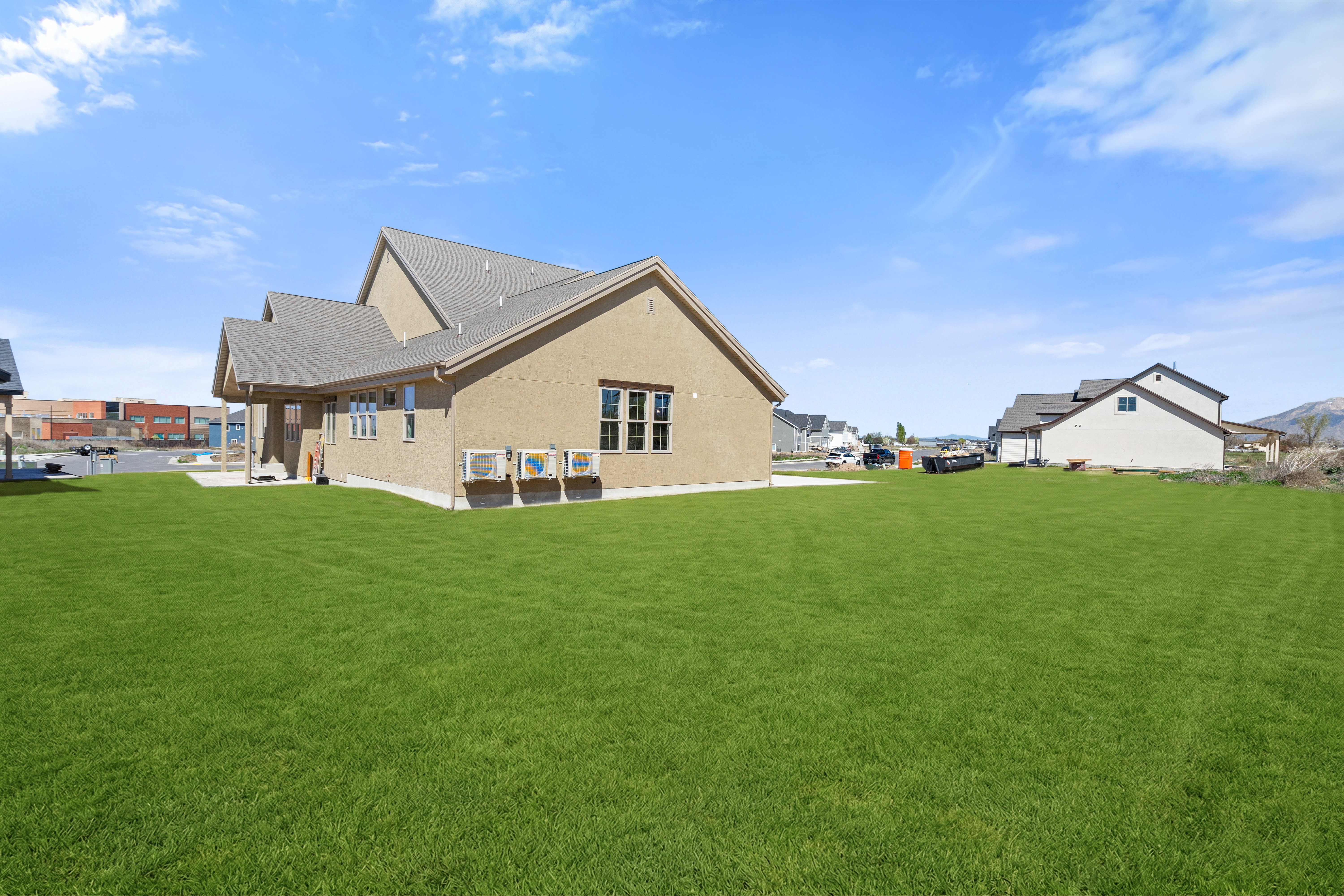 Rear view of house featuring a yard, stucco siding, and roof with shingles