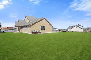 Rear view of house featuring a yard, stucco siding, and roof with shingles