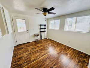Foyer entrance with dark wood-style flooring, a textured ceiling, and ceiling fan
