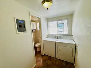Laundry room featuring a textured wall, independent washer and dryer, and a textured ceiling