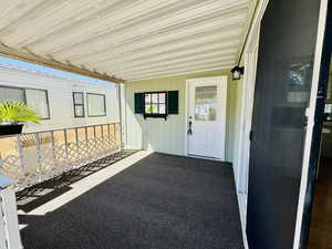 Doorway to property with an attached carport and a patio
