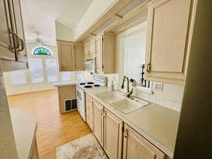 Kitchen with light wood finish cabinets, white appliances, light countertops, light wood-style flooring, and a ceiling fan