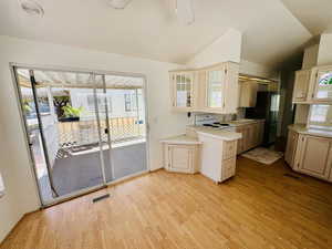 Kitchen featuring light countertops, white electric stove, light wood-type flooring, lofted ceiling, and freestanding refrigerator