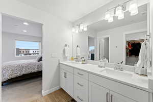 Full bath with double vanity, wood tiled floors, connected bathroom, a spacious closet, and recessed lighting