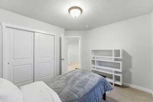Bedroom featuring light colored carpet, a closet, and a textured ceiling