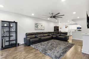 Living room with light wood-type flooring, ceiling fan, and recessed lighting