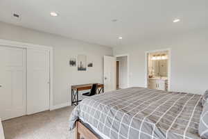 Bedroom featuring a closet, light colored carpet, recessed lighting, and ensuite bathroom