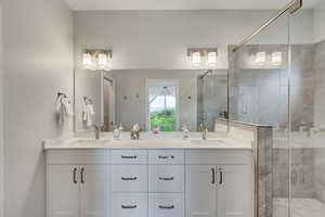 Bathroom featuring double vanity and a shower stall