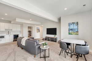 Living area with recessed lighting, beverage cooler, and light colored carpet