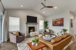 Living room featuring a ceiling fan, wood finished floors, a stone fireplace, and recessed lighting