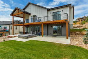 Rear view of house with a patio area, board and batten siding, a lawn, and a wooden deck