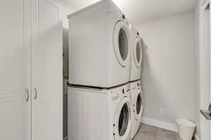 Laundry area featuring baseboards and stacked washer and dryer